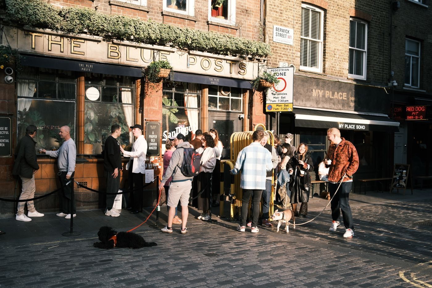Guests lined up behind a rope outside a busy pub