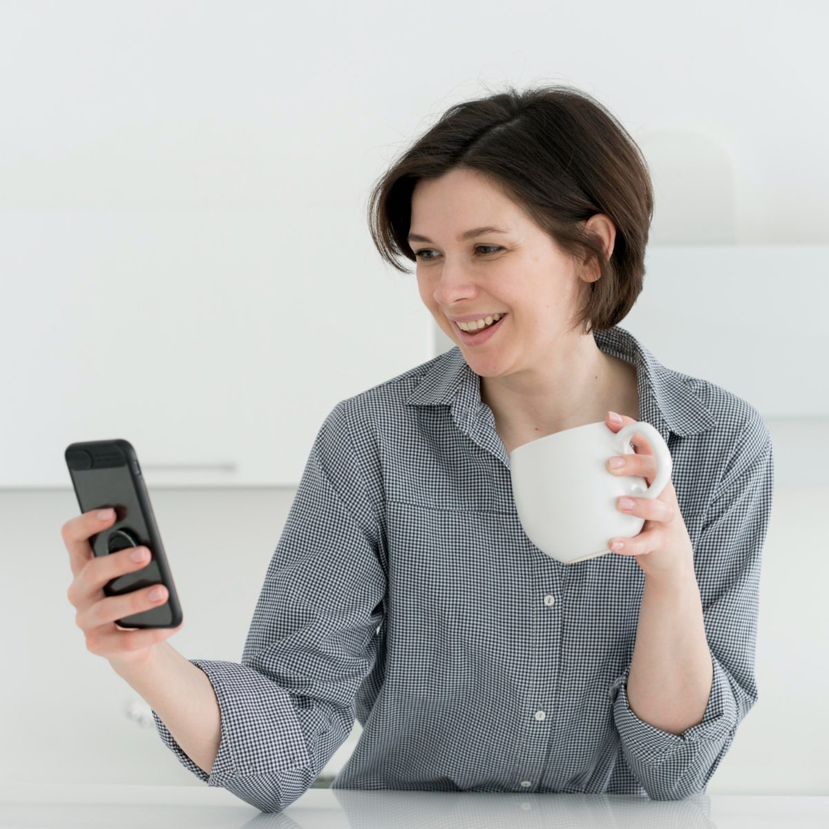 Woman with a coffee mug smiling at her phone as her entry time approaches