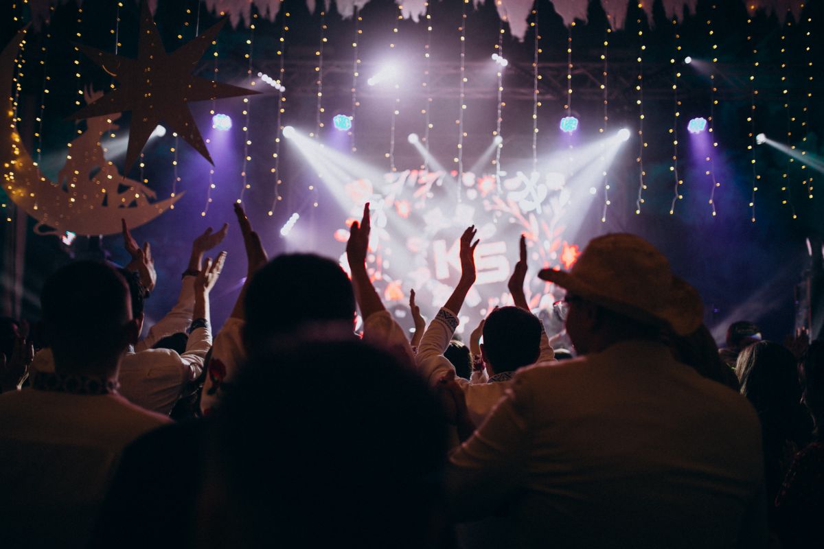 Crowd cheering in front of a lit stage at a live event